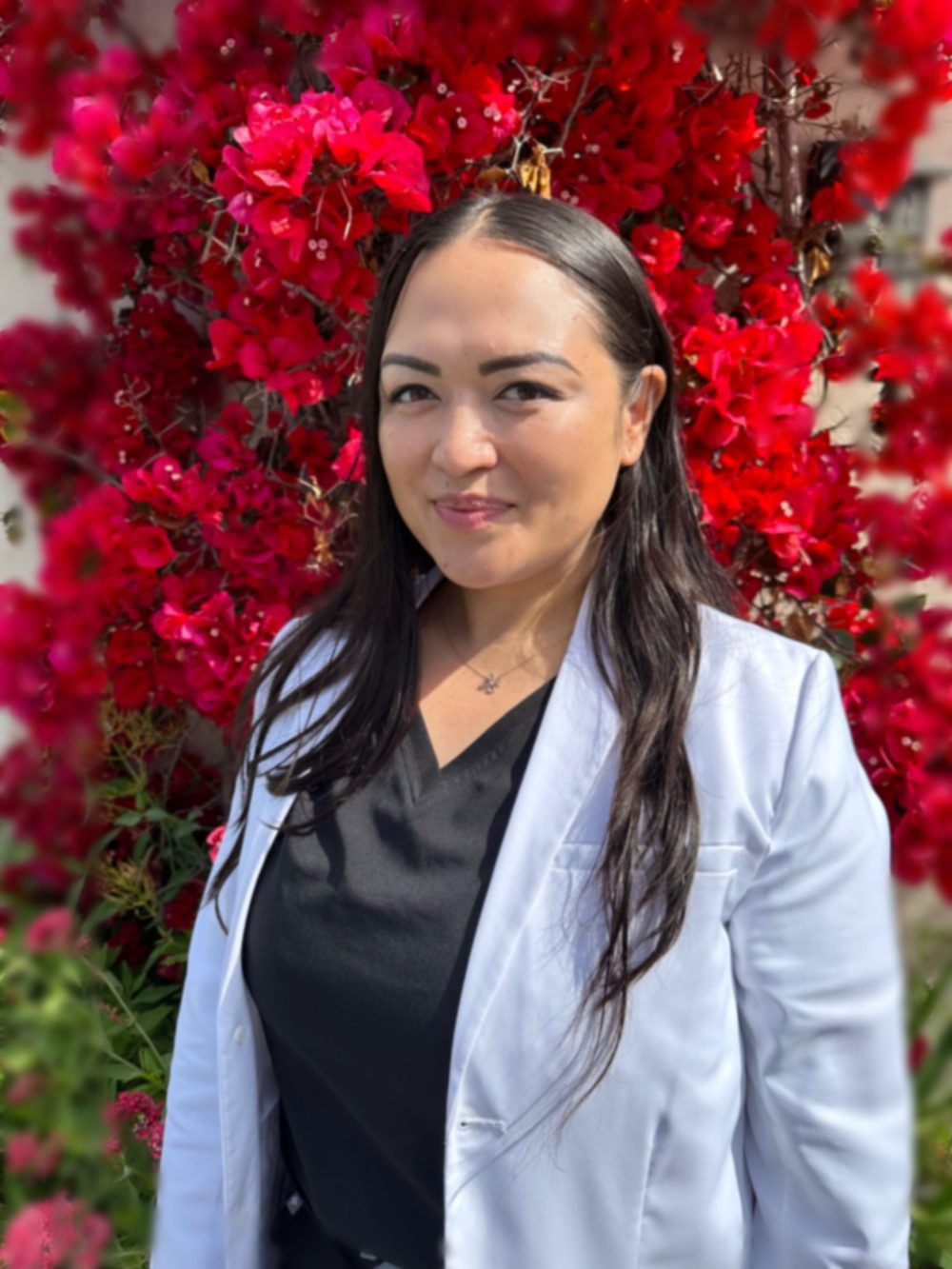 Christy Try in a white coat in front of a pink floral wall